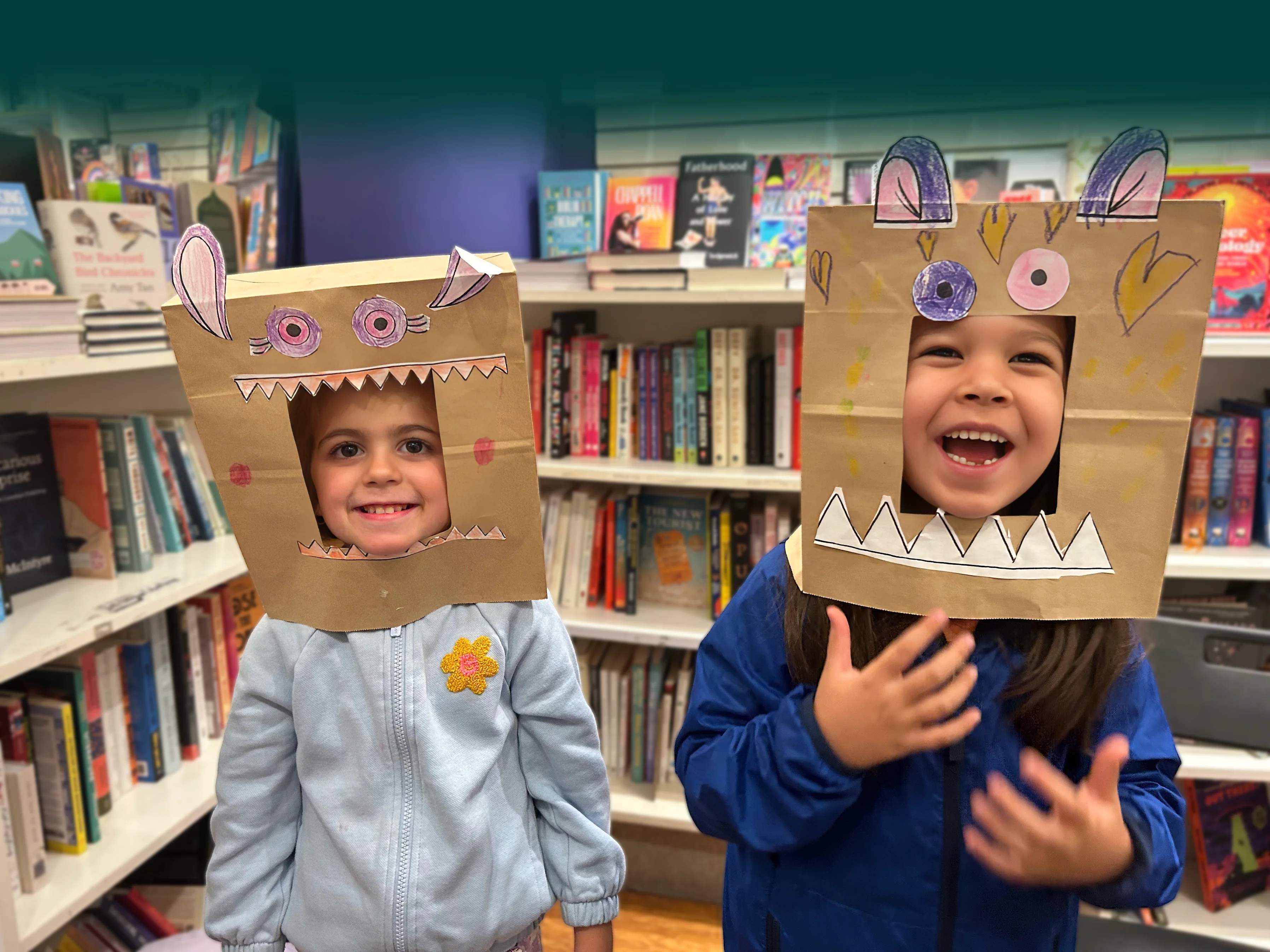 Two children wearing handmade cardboard animal masks in a bookshop