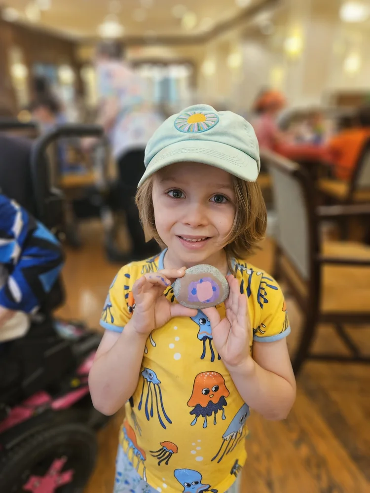 A child holding a painted rock at a Gedi program